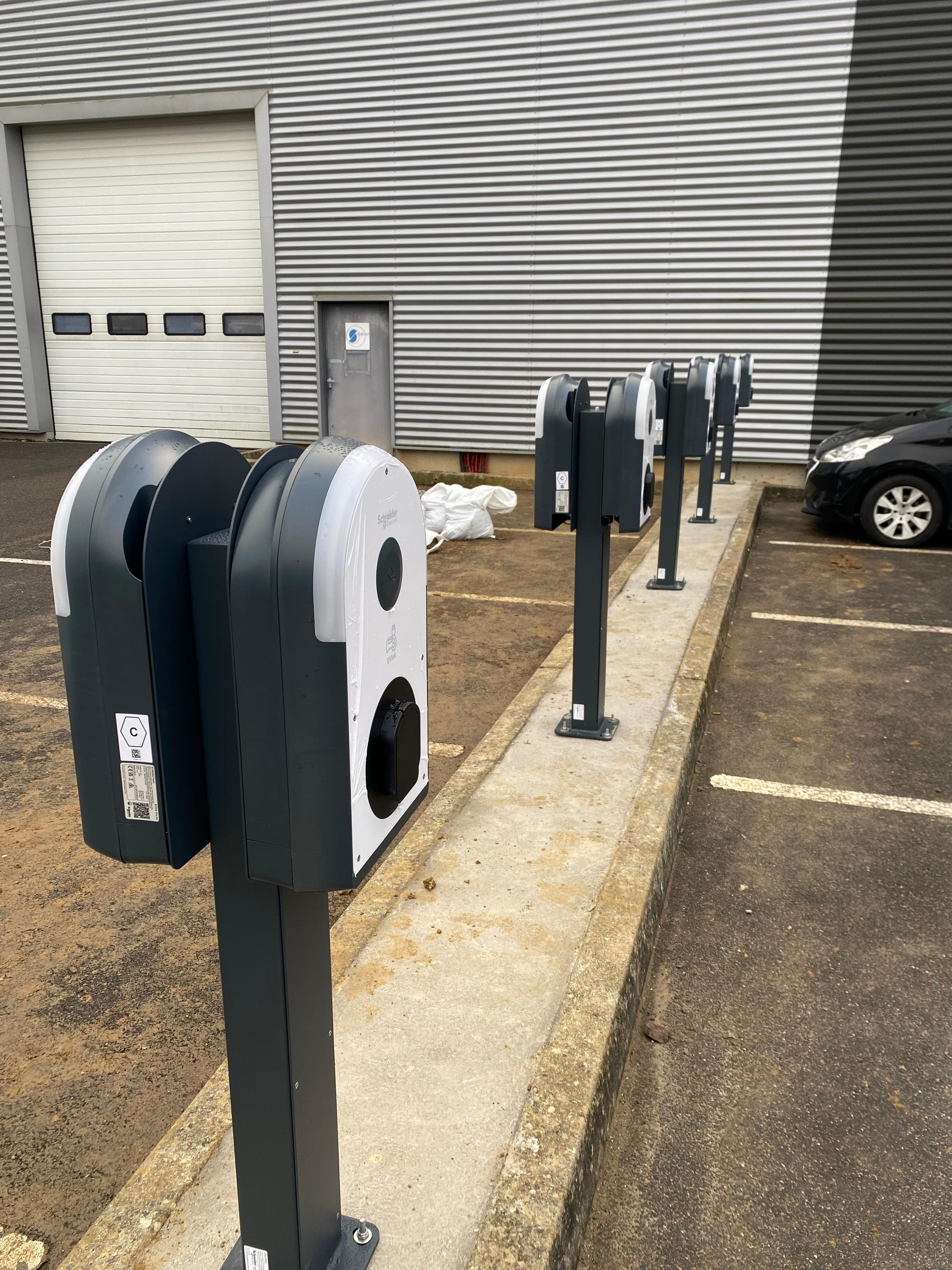 Installation de plusieurs bornes de recharge électrique alignées dans un parking collectif
